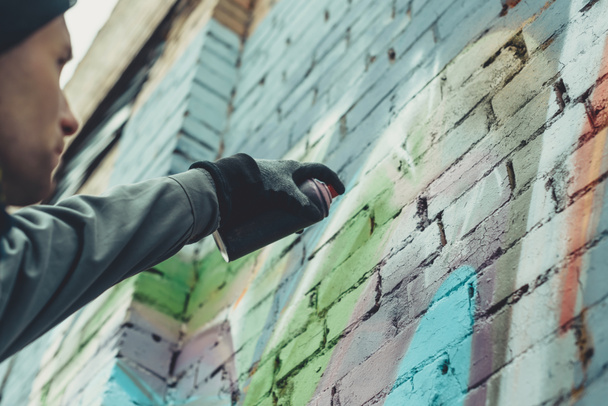 vista cortada de homem pintando grafite colorido na parede
 - Foto, Imagem