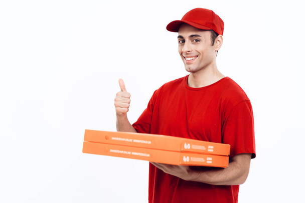 Man of Arab appearance works in the delivery of pizza. Man in red uniform is holding a box of pizza. - Фото, зображення