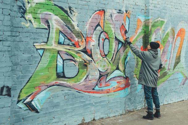 Straßenkünstler malt bunte Graffiti an Wand - Foto, Bild