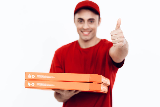 Man of Arab appearance works in the delivery of pizza. Man in red uniform is holding a box of pizza. - Fotoğraf, Görsel