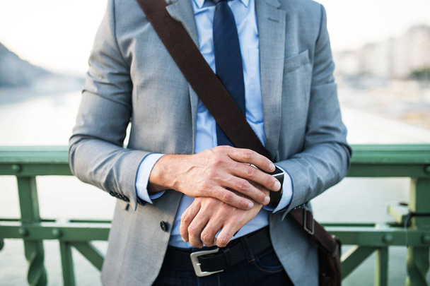 Businessman with smartwatch in a city. - Φωτογραφία, εικόνα