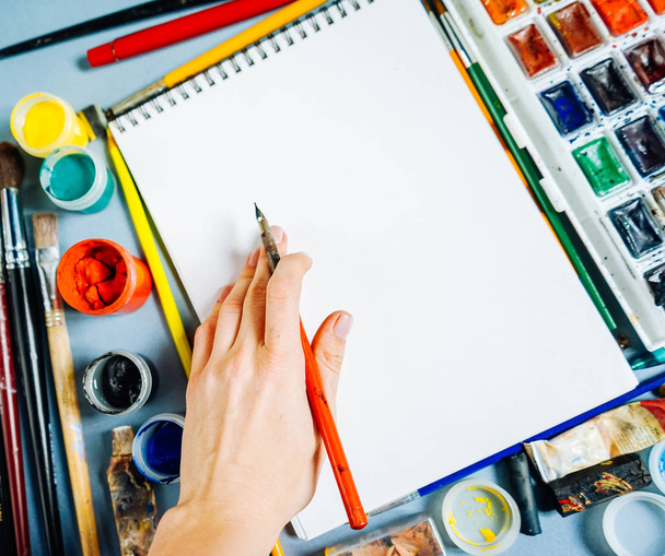 girl artist paints on white paper with watercolor paints, gouache, brushes - Fotografie, Obrázek