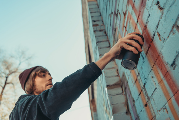 man painting colorful graffiti on wall of building - Photo, Image