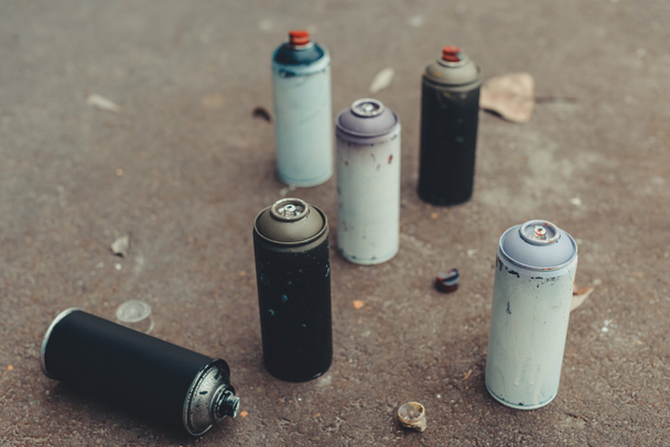 latas con pintura en aerosol de colores para graffiti sobre asfalto
 - Foto, imagen