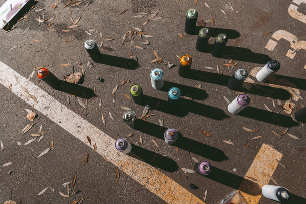 vista superior de latas con pintura en aerosol de colores para graffiti sobre asfalto
 - Foto, imagen