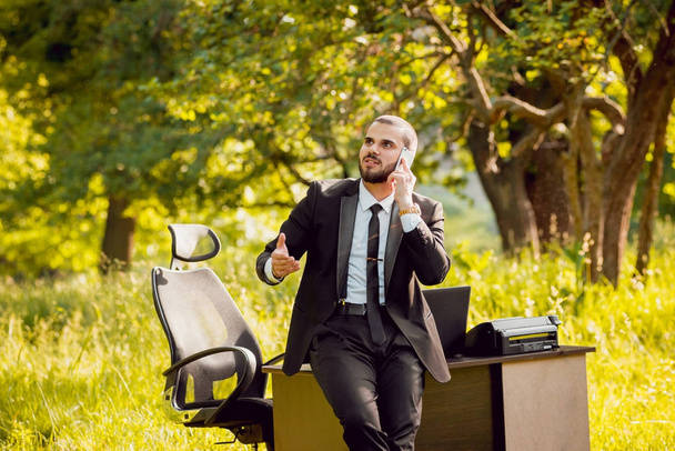 Young businessman at work in park. Concept of remote work. - Foto, afbeelding
