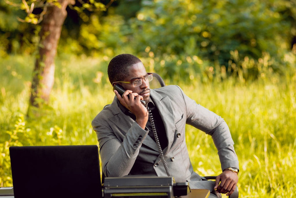 Young african american businessman at work in park. Concept of remote work. - Foto, afbeelding