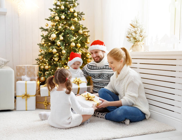 familie moeder vader en kinderen thuis op kerstochtend - Foto, afbeelding