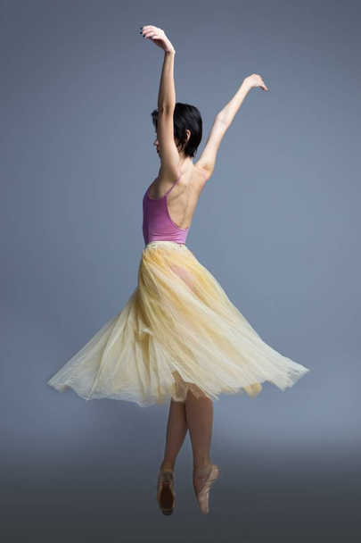 ballerina is dancing in the studio on a gray background - Foto, Imagem