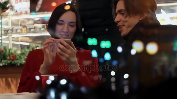 Jong koppel glimlachend praten over iets zitten in Cafe in avond - Video