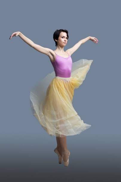 ballerina is dancing in the studio on a gray background - Photo, Image