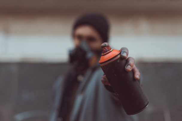 Straßenkünstler in Atemschutzmaske mit Sprühfarbe im Fokus - Foto, Bild