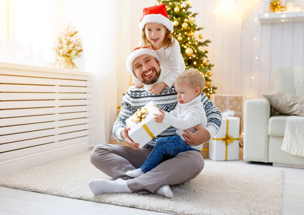 onnellinen perhe isä ja lapset leikkivät lähellä joulukuusi
 - Valokuva, kuva