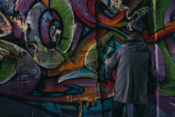 arrière vue de rue artiste peinture graffiti avec aérosol peinture sur mur la nuit
 - Photo, image