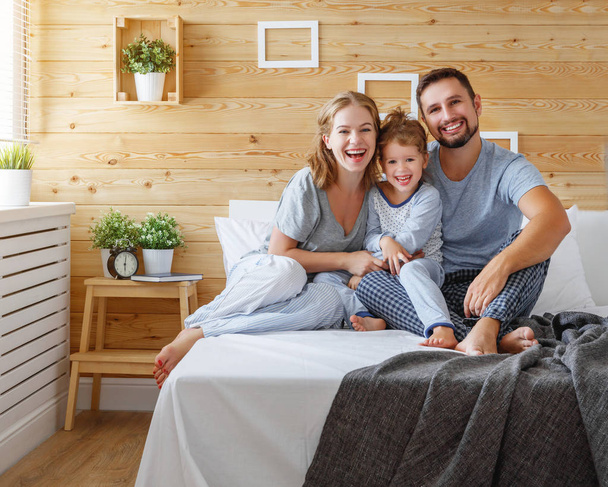 família feliz mãe, pai e filho ri na cama
 - Foto, Imagem
