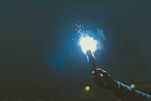 vista recortada de la mano masculina con bomba de humo en la noche
 - Foto, Imagen