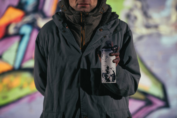 vista cortada do homem segurando lata com tinta aerossol à noite
 - Foto, Imagem