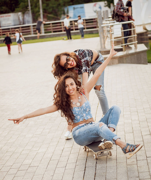 Two young girls having fun with skateboard outdoors - Фото, изображение