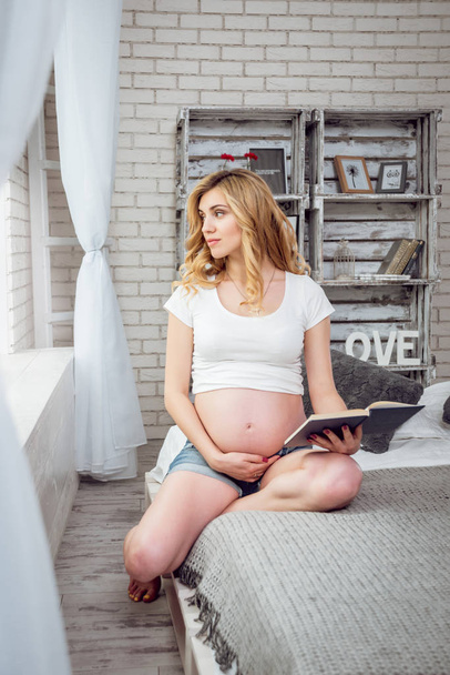 Young pregnant woman reading a book - Fotó, kép