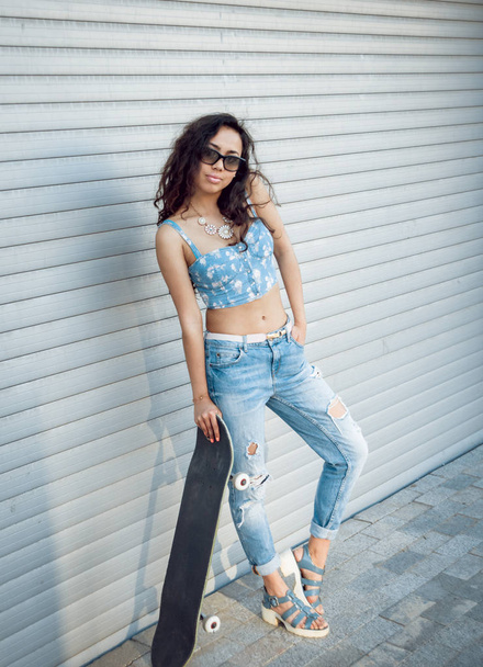 Young mixed race girl posing with skateboard outdoors - Fotó, kép