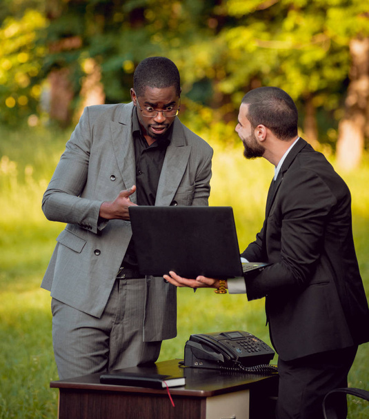 Two young multicultural businessmans at work in the park. Concept of remote work. - Foto, Imagem