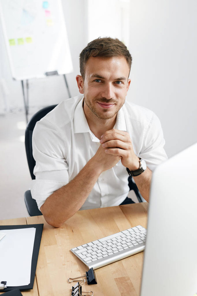 Молодой бизнесмен работает за компьютером в офисе
. - Фото, изображение