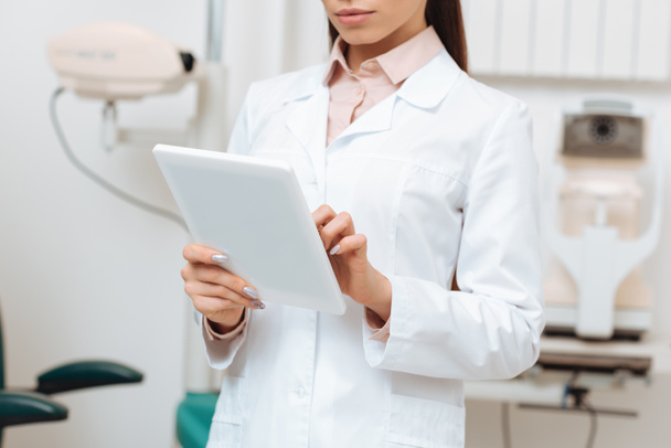 cropped shot of optometrist using digital tablet in hands in clinic - Photo, Image