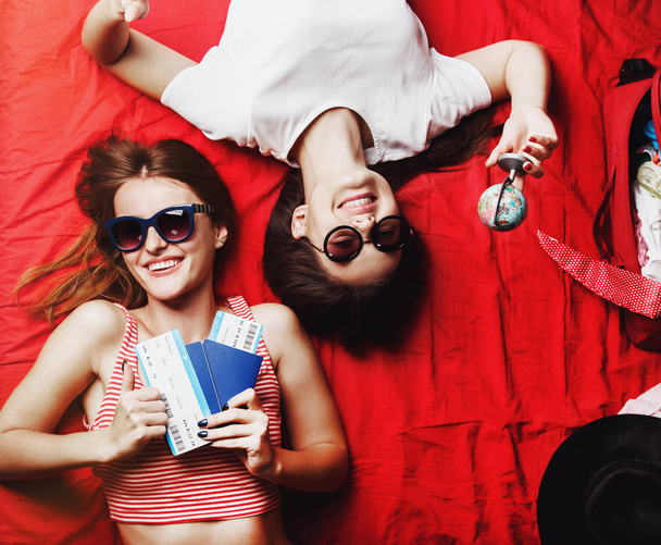İki kız arkadaş kırmızı yatakta yatarken - Fotoğraf, Görsel