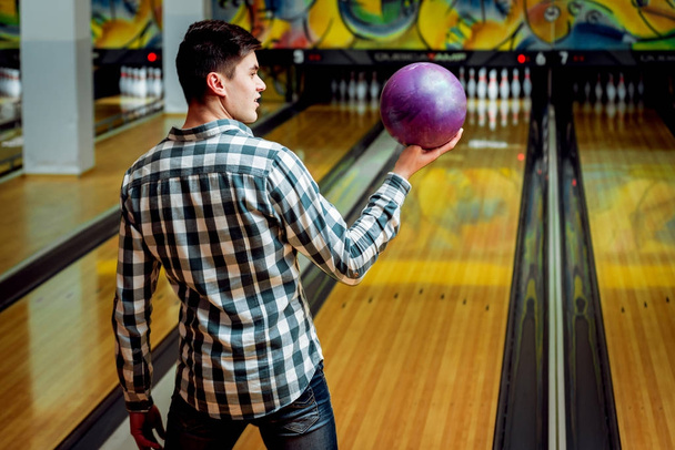 Young caucasian man having fun at the bowling club - Foto, afbeelding