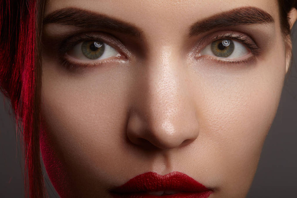 Closeup portrait with of beautiful woman face. Red color of fashion lip makeup, clean shiny skin and strong eyebrows - Photo, image