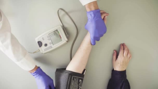 Médico midiendo la presión arterial de la mujer mayor
 - Metraje, vídeo
