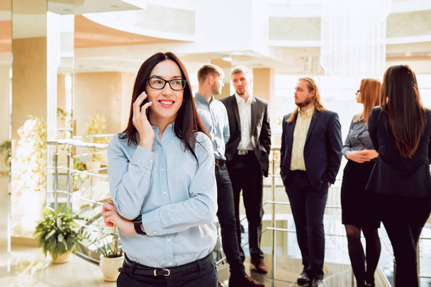 Biznes kobieta rozmawia przez telefon przed spotkaniem z kolegami. Biuro Rutynowa. - Zdjęcie, obraz