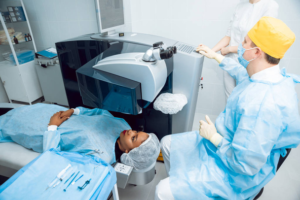Mujer afroamericana joven comprobando su visión con el oftalmólogo. Equipos médicos
. - Foto, Imagen