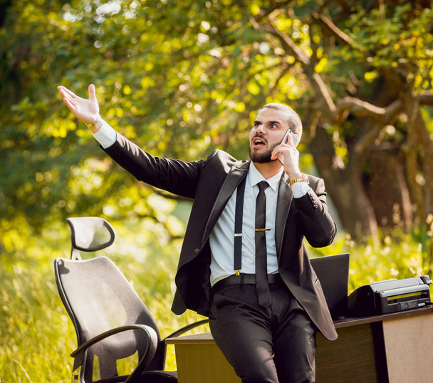 Young buisnessman with beard working in park. Concept of remote work. - 写真・画像