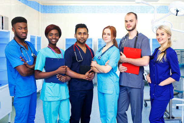 Багаторасова команда молодих лікарів у лікарні, що стоїть в операційній кімнаті
 - Фото, зображення