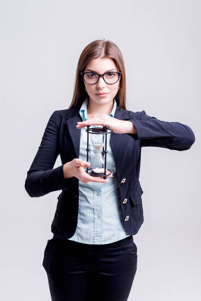 Young businesswoman holding an hourglass. Concept of deadline. - Foto, afbeelding