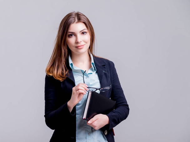 Young businesswoman with glasses before light grey wall - Foto, imagen