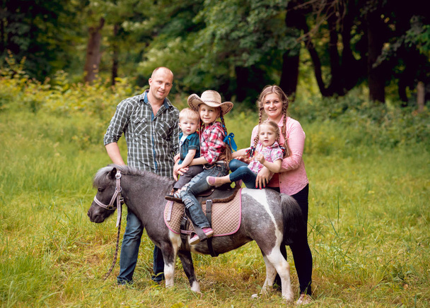 Cheerful family walks with pony horse in park - Valokuva, kuva