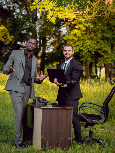 Two young multicultural businessmans at work in the park. Concept of remote work. - Foto, immagini