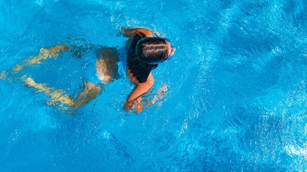 Aerial top view of girl in swimming pool water from above, tropical vacation holiday concept - Photo, image
