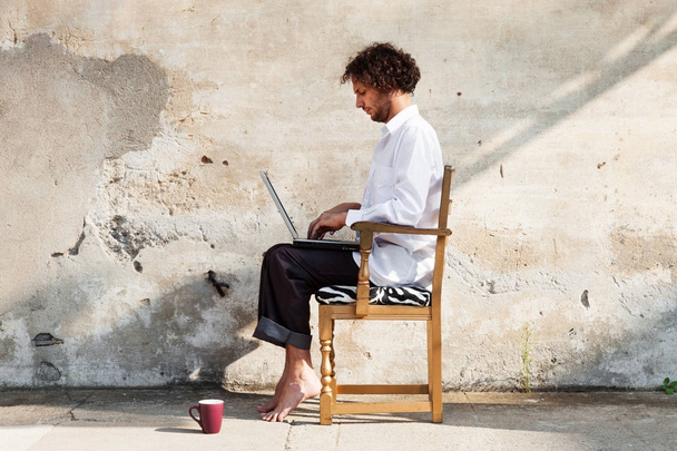 Portrait of a young man on a wall, with laptop - Φωτογραφία, εικόνα