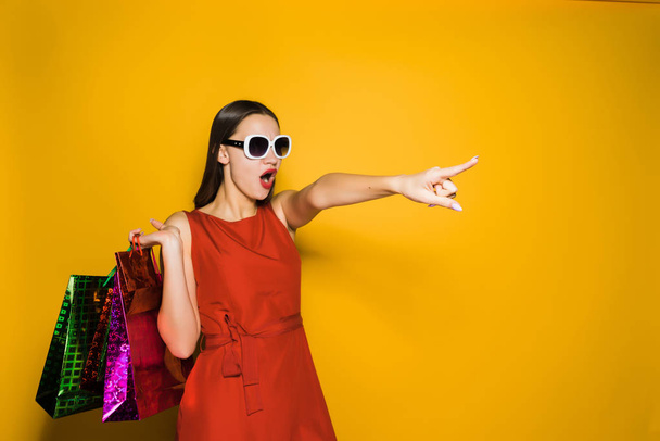 stylish girl in sunglasses went shopping with a surprised finger at something - Foto, Imagen
