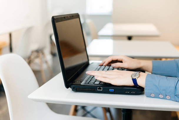 meisje freelancer in blauw shirt werken hard op laptop in café - Foto, afbeelding