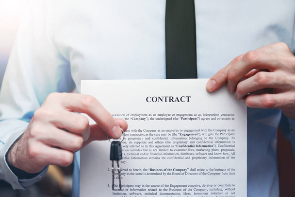 Успешный бизнесмен предлагает ключ с контрактом. Договор аренды с договором
 - Фото, изображение