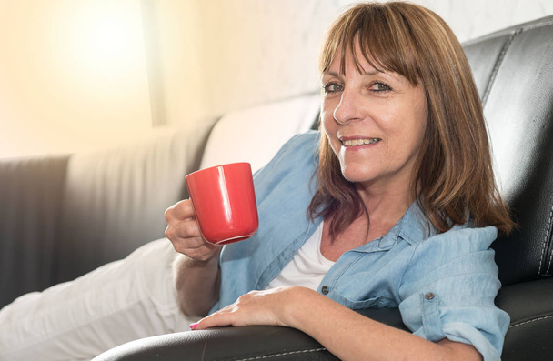 Mature woman during coffee break at home, light effect - Photo, Image