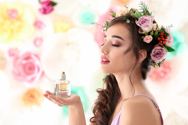 Beautiful young woman with bottle of floral perfume on color background - Фото, зображення