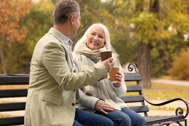 Happy mature couple resting on bench in park - Φωτογραφία, εικόνα