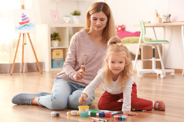 Mother with cute girl painting picture on sheet of paper, indoors - Photo, Image