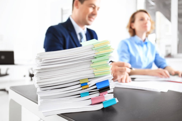 Montón de documentos sobre la mesa y los trabajadores borrosos en la oficina
 - Foto, Imagen
