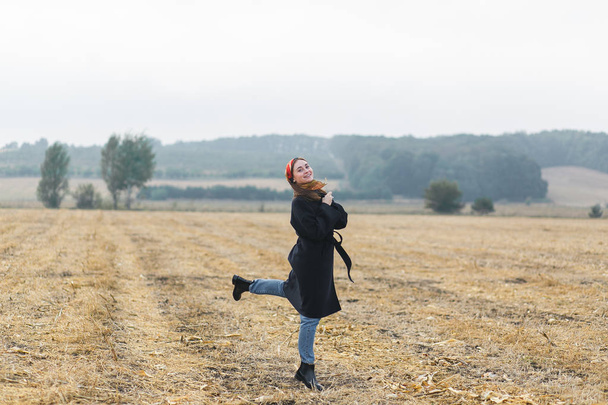 Picture of happy cheerful woman having fun on wheat field, beautiful brunette with raised up hands enjoying freedom outdoors, agriculture lifestyle, autumn harvest concept, fall season - Photo, Image